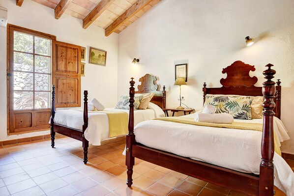 Un dormitorio con dos camas de madera, una pared de piedra y un ventanal grande.