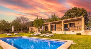 Una piscina con sillas de descanso y un área de patio techada.