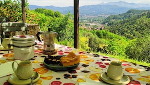 Un espace de restauration en plein air avec une table dressée pour un repas, offrant une vue sur un paysage montagneux.