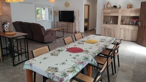 Een moderne woonkamer met een bank, televisie en een eethoek met tafel en stoelen.