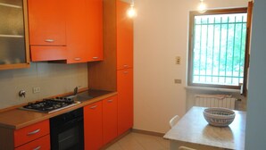 Una cocina con armarios naranjas, estufa a gas, lavabo y ventana con rejas.