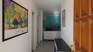 Un pasillo con una zona de cocina, una mesa de comedor y una puerta de madera.