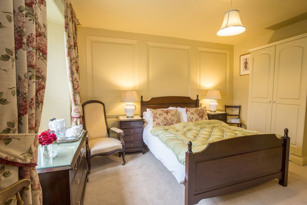 A bedroom with a bed, bedside tables, a chair, a desk, and a wardrobe.