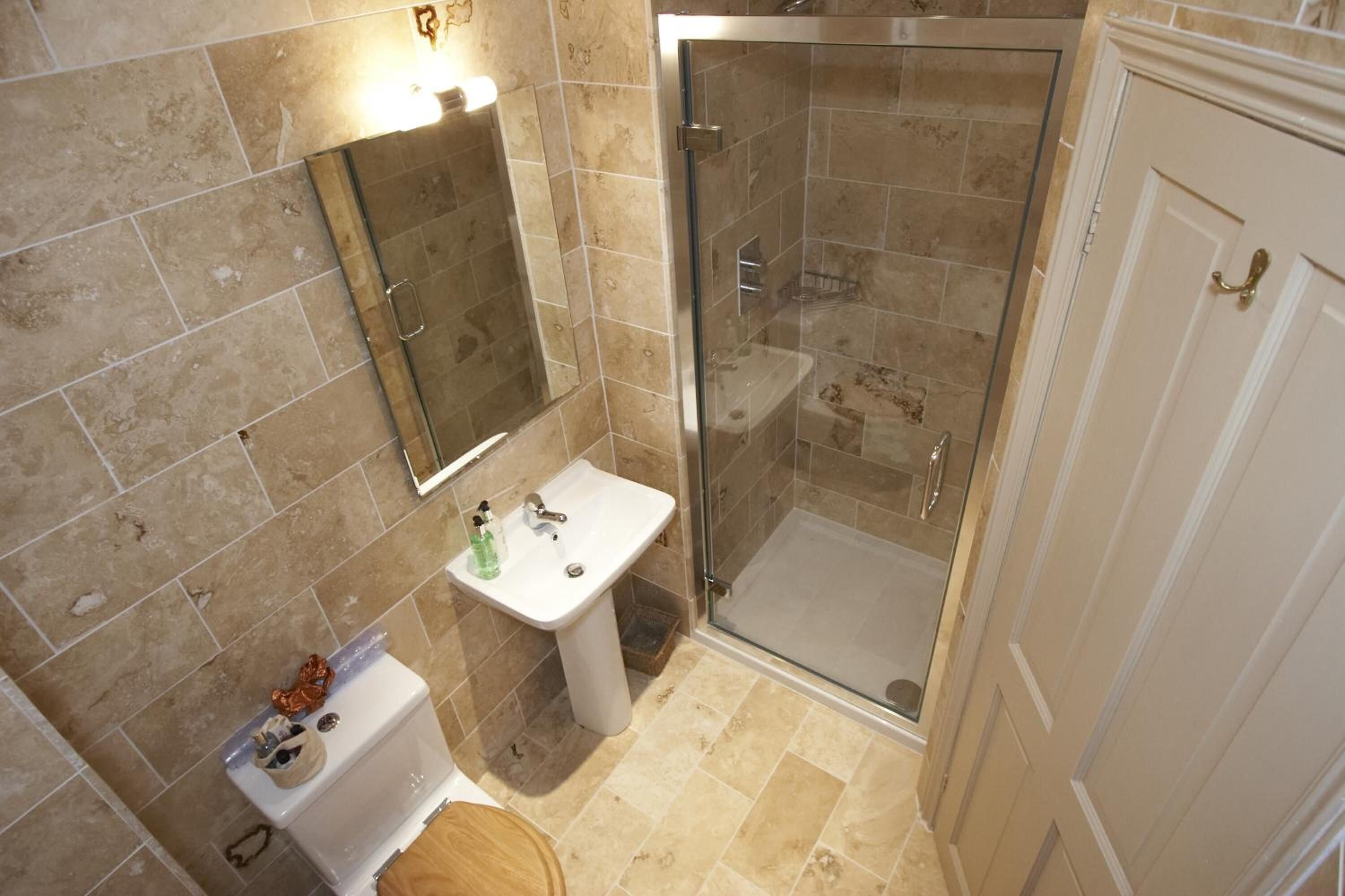 Un baño con ducha envuelta en vidrio, lavamanos e inodoro.