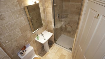 Un baño con ducha envuelta en vidrio, lavamanos e inodoro.