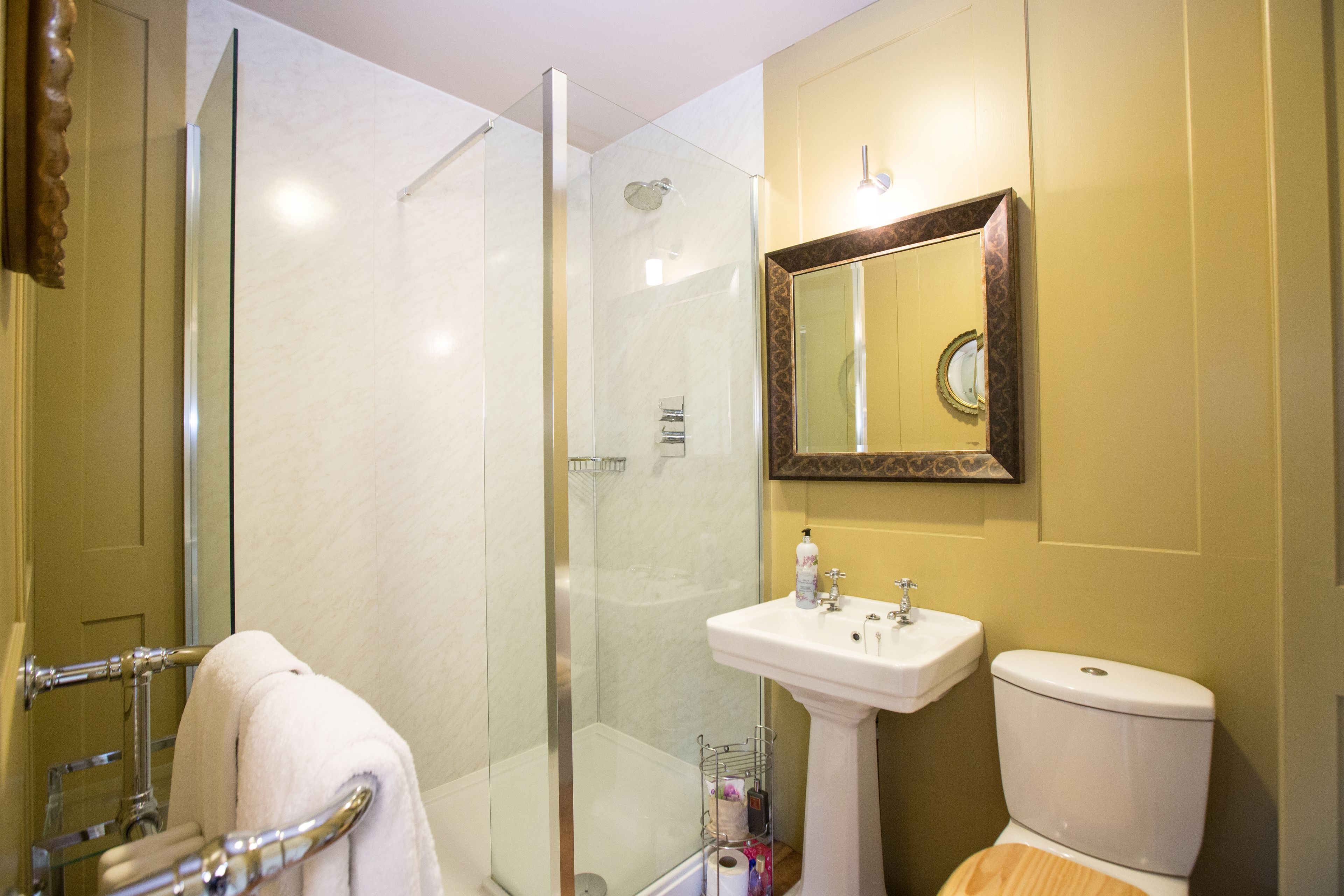 Ein Badezimmer mit Duschkabine aus Glas, Waschbecken in Weiß und Toilette.