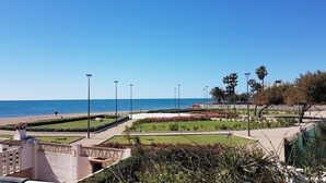 Un paseo marítimo junto a la playa, con jardines ajardinados y farolas.