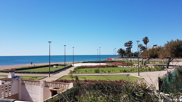 Un paseo marítimo junto a la playa, con jardines ajardinados y farolas.