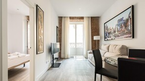 A modern hotel room with a bed, a sofa, a TV, and a painting on the wall. - PUERTA DEL SOL CITY CENTER WITH BALCONY (Madrid)