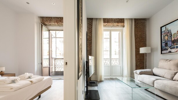 A modern hotel room with a bed, a sofa, a TV, and a balcony. - PUERTA DEL SOL CITY CENTER WITH BALCONY (Madrid)