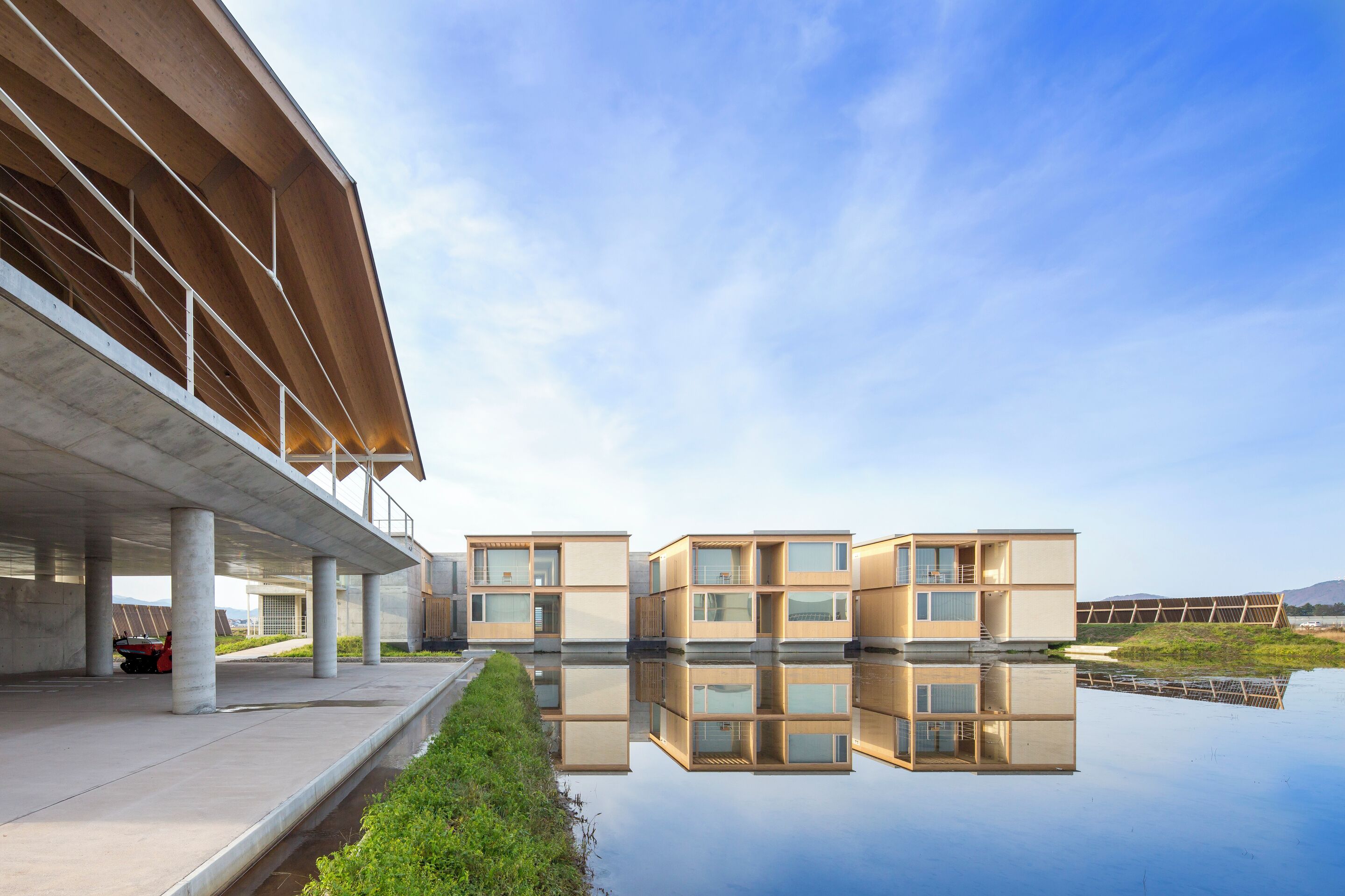A modern building with a reflective water surface in front.
