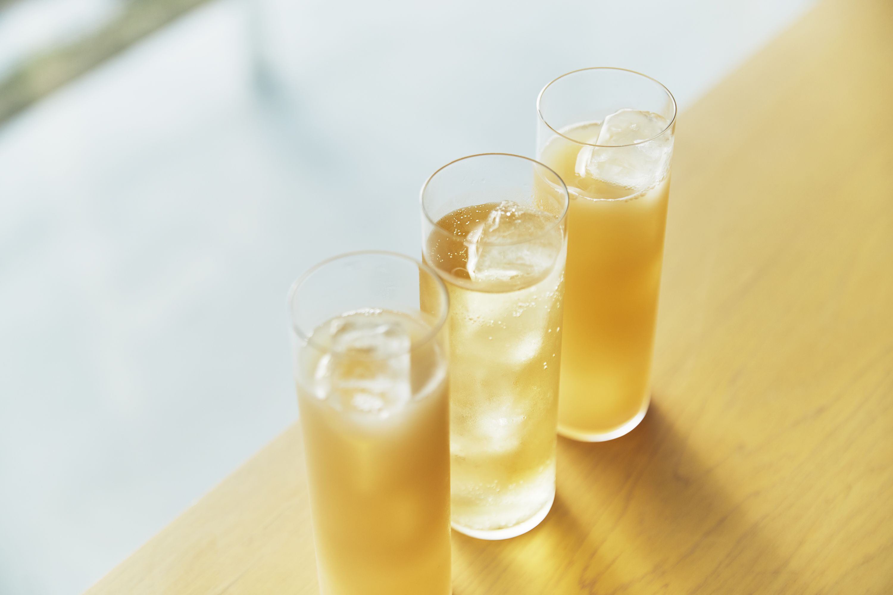 Tres vasos de bebida helada sobre una superficie de madera.