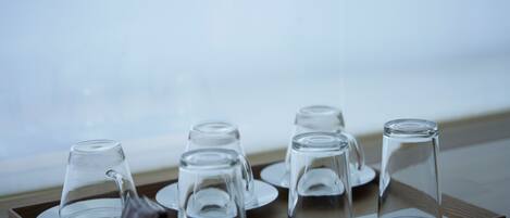 A tray with several clear wine glasses and a small container, likely for condiments, on a wooden surface.