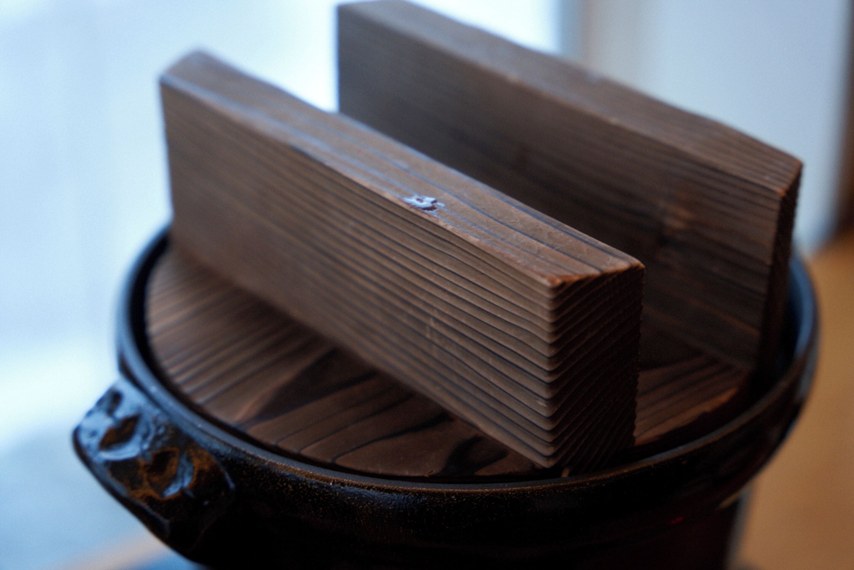 A stack of dark brown wooden blocks in a black container.