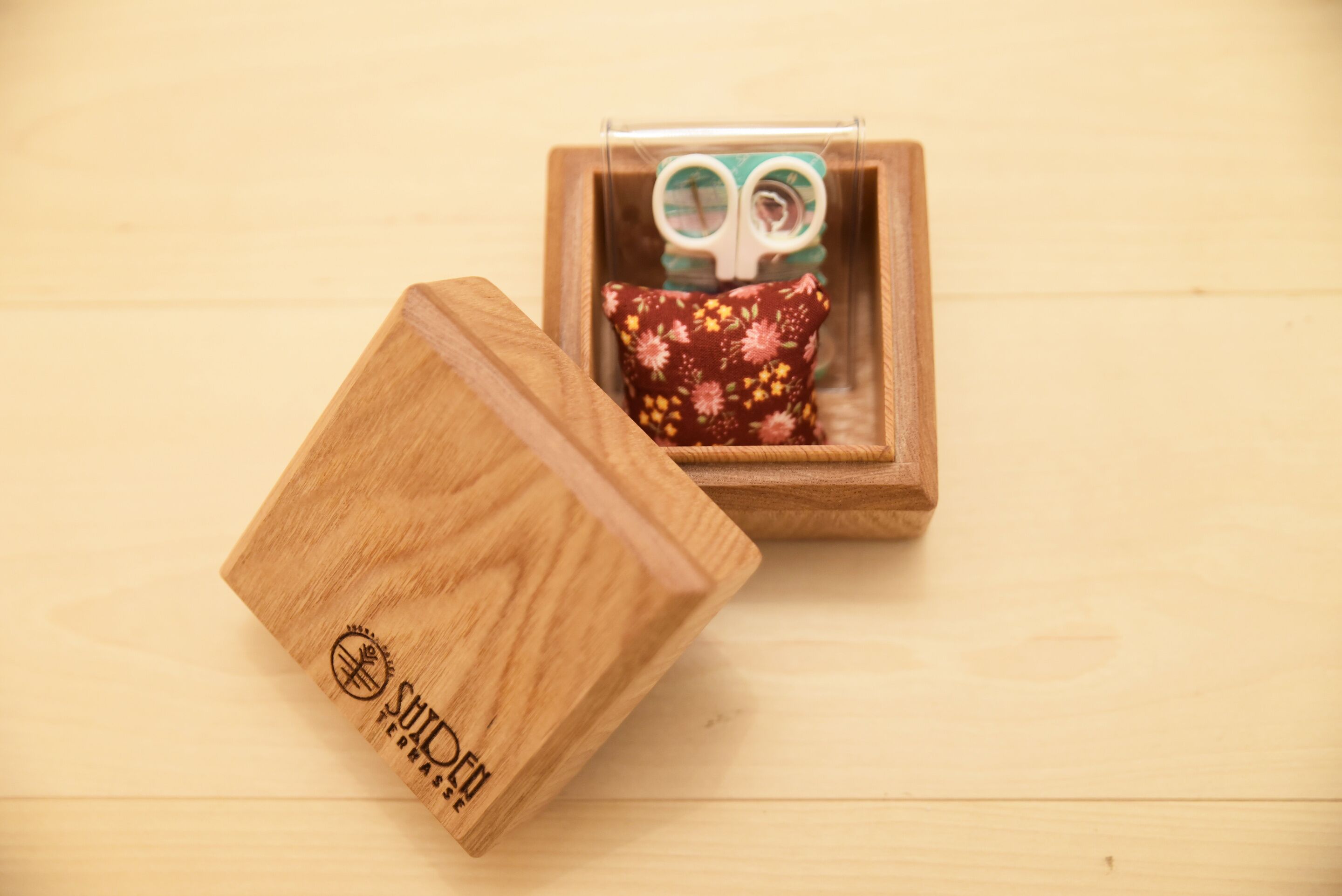 Una caja de madera con un cojín floral, colocada sobre una superficie de madera.