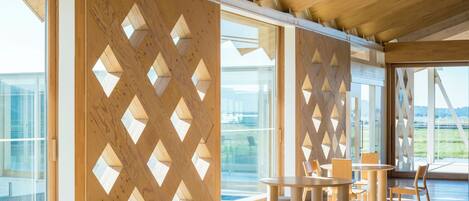 Un espacio interior amplio con muebles de madera y ventanas grandes.