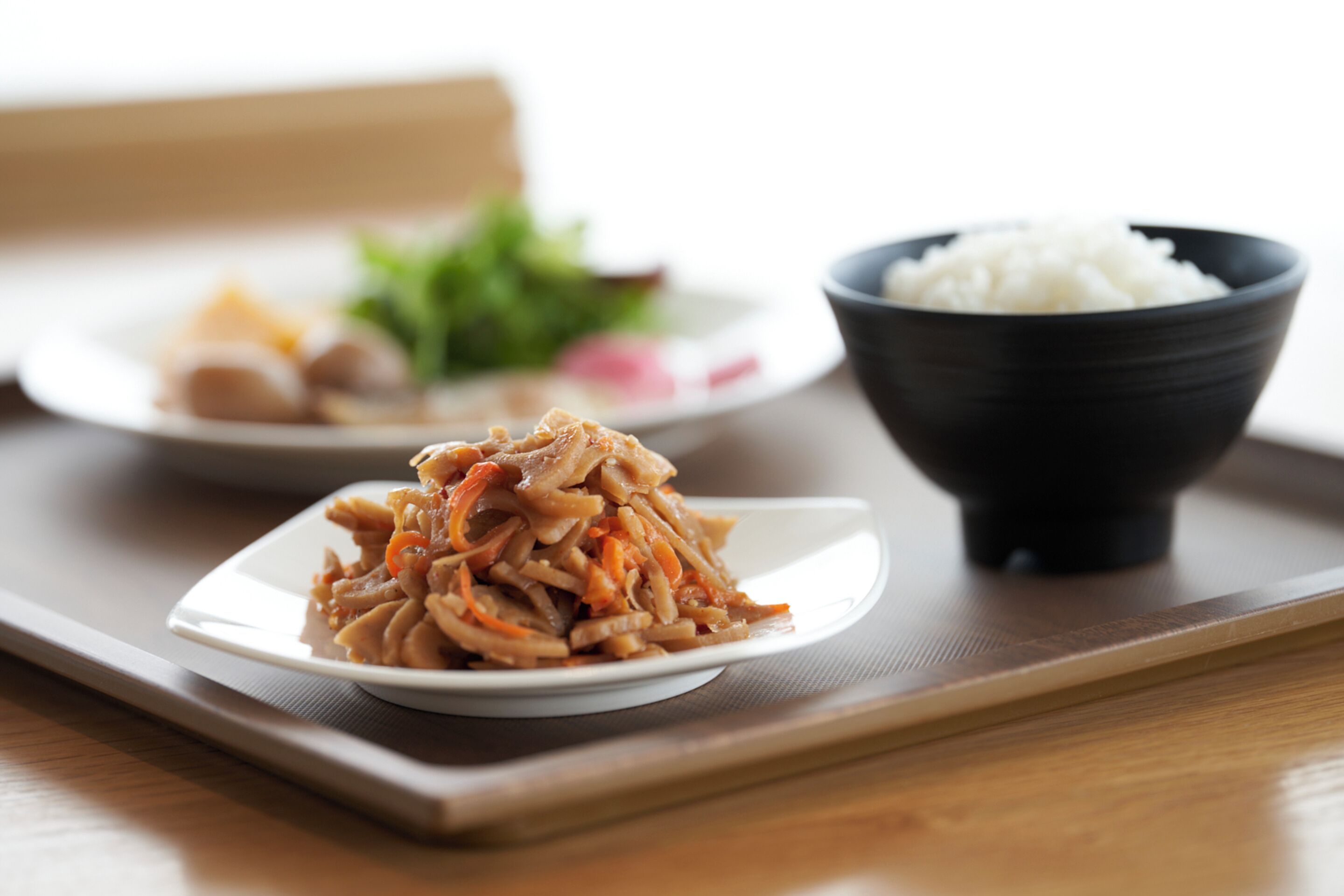A tray with a plate of stir-fried vegetables and a bowl of white rice.