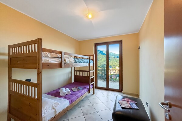 A bunk bed room with a view of a mountainous landscape through a glass door.
