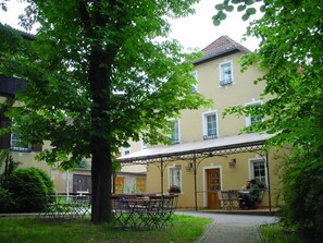 A courtyard with outdoor seating, a covered area, and a building with a tiled roof. - Gast Pensions Haus Hodes (Rudolstadt)
