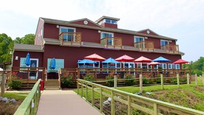 A two-story building with a wooden deck and multiple umbrellas.