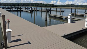 A wooden dock extending into calm water with multiple piers and a clear sky.
