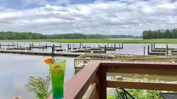 A view of a lake with docks, a wooden deck, and a glass of a green beverage with a garnish.