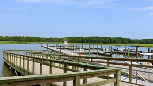 A wooden dock extending into a calm lake with boats docked at a pier.