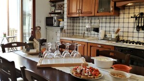 A kitchen with wooden cabinets, a tiled backsplash, and a dining table set with wine glasses and a plate of food. - Chianti Best House - Comfort, relax & privacy in the center of Greve in Chianti (Greve in Chianti)