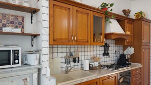 A kitchen with wooden cabinets, a microwave, a toaster, a sink, and a stove. - Chianti Best House - Comfort, relax & privacy in the center of Greve in Chianti (Greve in Chianti)
