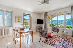Un comedor con una mesa, sillas, televisor y vistas al exterior.