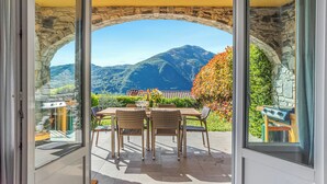 A patio with a stone archway, wicker furniture, and a view of mountains.