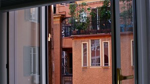 A view from a window with a partially open door, revealing a building with multiple windows and balconies. - Empire Suites (Rome)