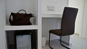 A chair and a brown bag on a white shelf in a room with a white wall and a white floor. - Empire Suites (Rome)