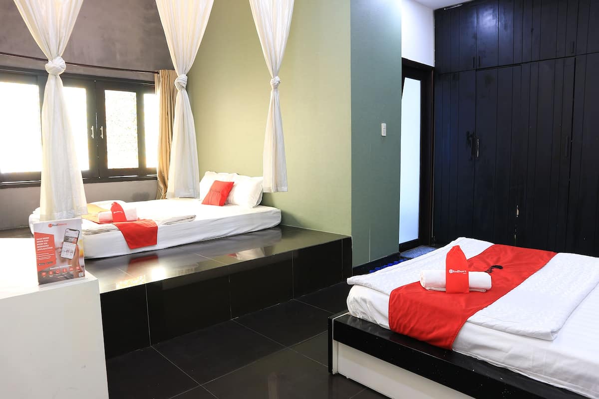 A hotel room with two beds, a large wardrobe, and a reception area with a phone and a brochure.