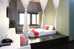 A hotel room with a bed, curtains, a bedside table with a remote control, and a brochure. - RedDoorz near Gia Dinh Church (Ho Chi Minh City)