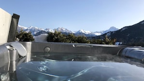 Uma banheira de hidromassagem com vista desobstruída para montanhas cobertas de neve ao fundo.