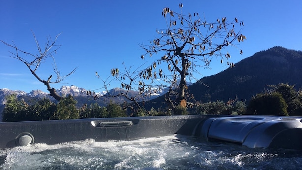 Área de nascente termal com vista para montanhas e uma árvore em primeiro plano.
