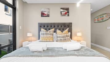 A bedroom with a large bed, two nightstands, two lamps, and artwork on the wall.