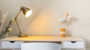 A desk with a lamp, a decorative bird, and a vase with dried plants. - Eden on the Bay 125 (Cape Town)