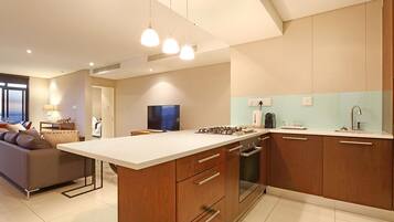A modern kitchen with a central island, wooden cabinets, and a built-in oven.