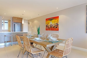 Un comedor moderno con una mesa de madera preparada para seis personas, rodeada de sillas de mimbre.