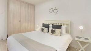 Une chambre à coucher comprenant un lit, deux tables de chevet, une commode, une armoire et des décorations murales en forme de cœur.