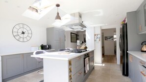 Una cucina moderna con isola centrale, mobili grigi, un orologio grande e un lucernario.