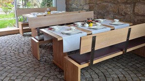 A wooden bench and table set up outdoors with white tablecloths and tea sets. - RotHweinHotel (Wiesenbronn)