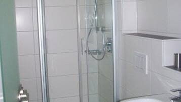 A bathroom with a glass-enclosed shower, a white toilet, and a sink.