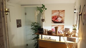 A reception desk labeled 'Wellness' with a plant, decorative lights, and a framed picture on the wall. - RotHweinHotel (Wiesenbronn)