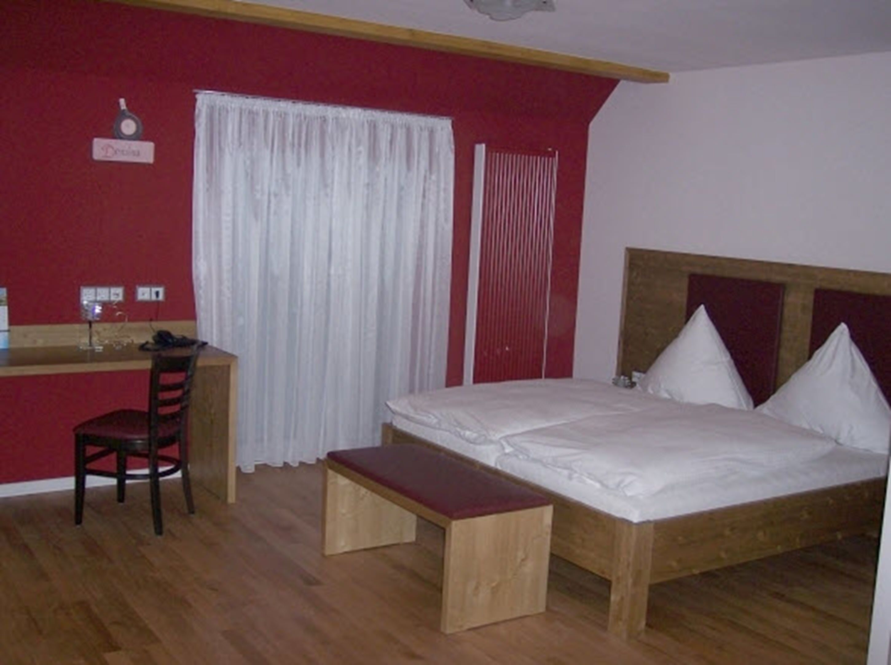 Ein Schlafzimmer mit einem hölzernen Bett, einem Schreibtisch aus Holz, einem Stuhl und einer Bank.