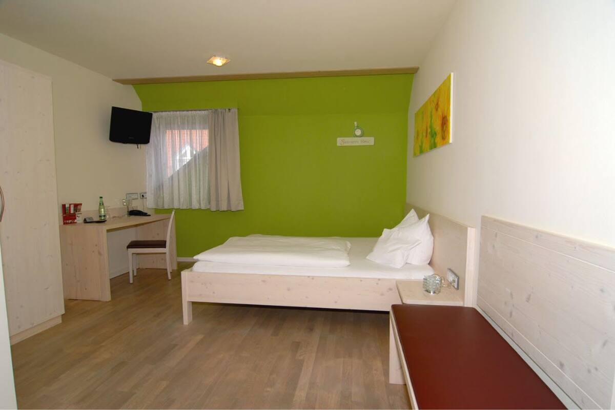 Ein Zimmer mit einem Bett, einem Schreibtisch und einem Stuhl.
