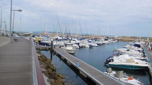 A marina with numerous boats docked along a wooden pier. - Window to the Sea Oeiras (Oeiras)