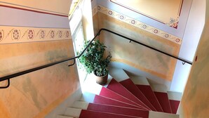 A staircase with alternating red and white steps, a handrail, and a potted plant at the bottom.